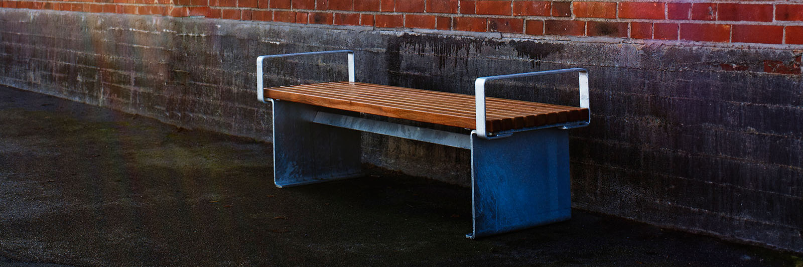 Un beau banc de parc robuste avec une structure en acier et des accoudoirs le long d'une allée.